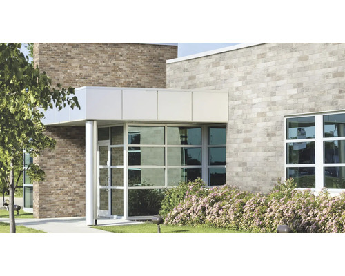 Fassade eines modernen Geschäftsgebäudes mit hellen und dunklen Ziegeln, großflächigen Glasfronten und einem überdachten Eingangsbereich.