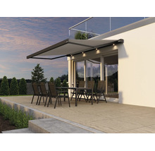 Moderne Terrassenmarkise mit integrierter LED Beleuchtung über einer Sitzgruppe auf einer Terrasse vor einer Hausfassade.