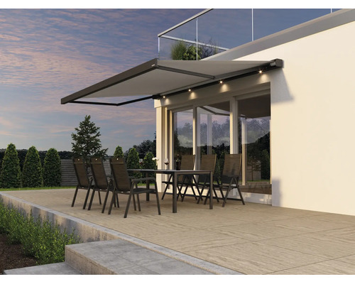 Moderne Terrassenmarkise mit integrierter LED Beleuchtung über einer Sitzgruppe auf einer Terrasse vor einer Hausfassade.