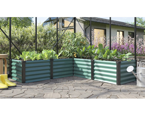 Winkel Hochbeet aus gewelltem Metall in einem Gewächshaus mit Pflanzen und Gießkanne auf einer Terrasse.