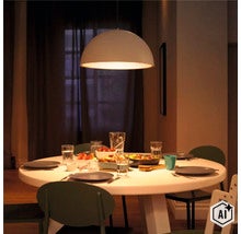 Moderne halbkugelförmige Hängeleuchte über einem runden Esstisch in einem gemütlich beleuchteten Esszimmer mit gedecktem Tisch (Image AI modified or generated)