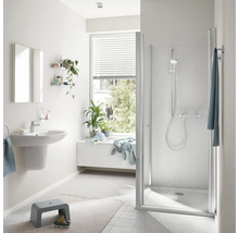 Modernes Badezimmer mit weißer Duschkabine, Waschbecken, Spiegel und bodengleicher Duschwanne, hell und funktional eingerichtet.