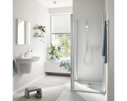 Modernes Badezimmer mit weißer Duschkabine, Waschbecken, Spiegel und bodengleicher Duschwanne, hell und funktional eingerichtet.