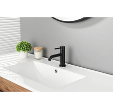 Moderne schwarze Waschtischarmatur an einem weißen Waschbecken in einem Badezimmer mit Zimmerpflanze und Kerze.
