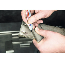 Eine Hand markiert mit einem Permanentmarker eine Metallplatte bei der Metallbearbeitung.