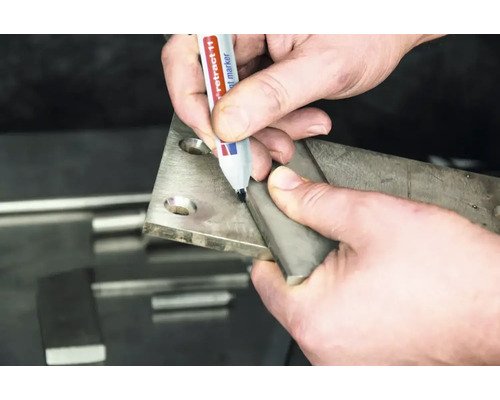 Eine Hand markiert mit einem Permanentmarker eine Metallplatte bei der Metallbearbeitung.
