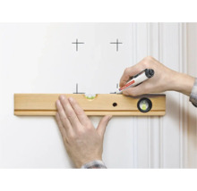 Eine Hand hält eine Wasserwaage aus Holz an einer Wand, während die andere Hand mit einem Edding Marker Markierungen setzt.