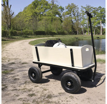 Ein hölzerner Handwagen mit Luftreifen steht auf einem Waldweg am Wasser.
