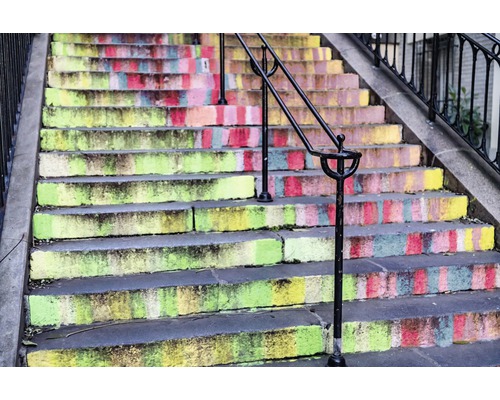 Treppe mit farbenfrohen Stufen und Geländer.