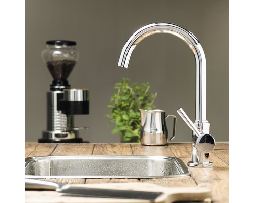 Küchenszene mit Spüle, Wasserhahn, Kaffeemühle und Kräutern