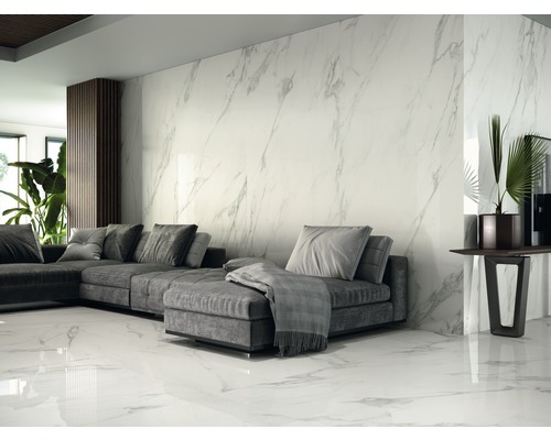 Helles Wohnzimmer mit grauer Couch, Zimmerpflanzen und Wand- sowie Bodenfliesen in Marmoroptik.