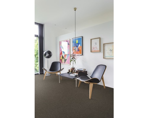 Wohnzimmer mit Teppichboden, zwei Stühlen und Kunstwerken an der Wand.