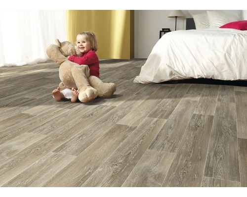 Heller Raum mit Laminatboden in Holzoptik, darauf ein Kind mit einem Teddybär