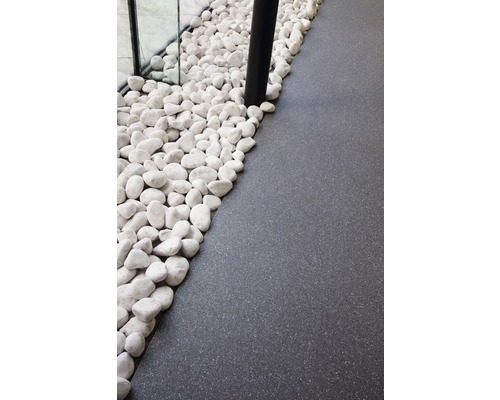 Dekorative weiße Kieselsteine neben dunklem Bodenbelag