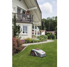 Rasenroboter auf einer Rasenfläche vor einem Wohnhaus