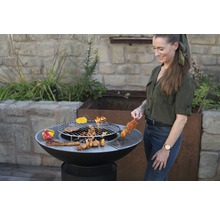 Frau grillt mit einer Feuerstelle im Garten.