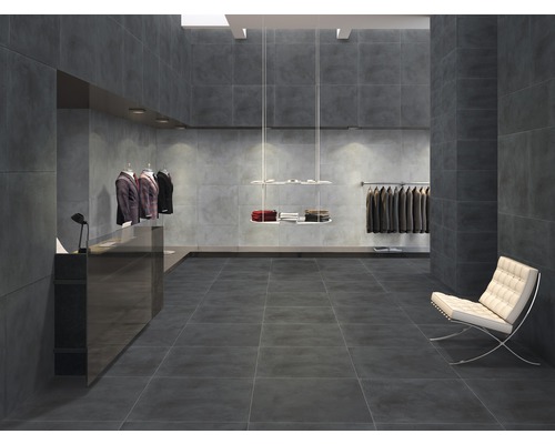 Innenraum mit grauen Fliesen an Boden und Wänden, heller Sessel