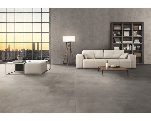 Wohnzimmer mit grauen Bodenfliesen, Sofa, Bücherregal und großem Fenster