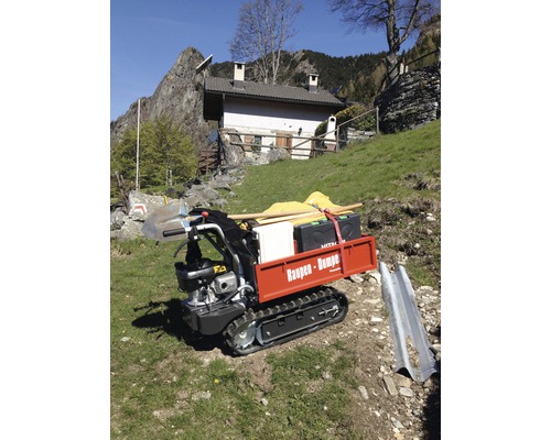 Raupendumper mit Ladung im Außeneinsatz vor einem Haus