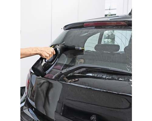 Eine Person reinigt mit einem Fenstersauger die Heckscheibe eines Autos.