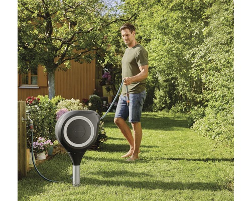 Gartenszene mit Schlauchbox und Mann, der einen Gartenschlauch hält.