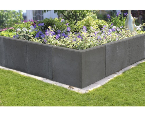 Hochbeet aus Betonsteinen mit blühenden Pflanzen im Garten