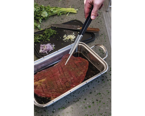 Marinierendes Steak mit Zange, Zwiebeln, Knoblauch und Kräutern