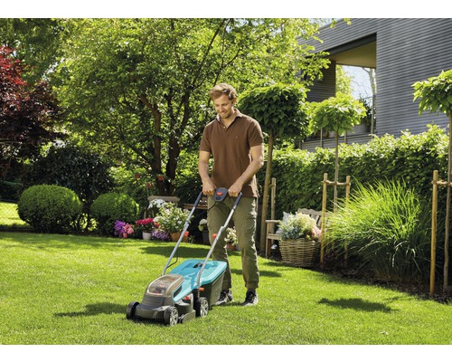 Ein Mann mäht den Rasen mit einem Rasenmäher in einem Garten.