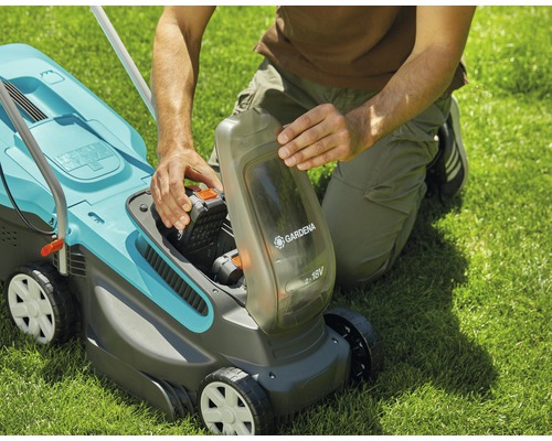 Eine Person setzt den Akku in einen Akku-Rasenmäher der Marke Gardena ein.