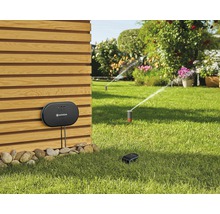 Szene mit Gartenbewässerungssystem mit Steuerungseinheit und Rasensprengern im Garten.
