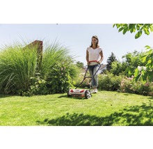 Frau benutzt Spindelmäher im Garten.