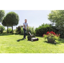 Mann benutzt Rasenlüfter im Garten.