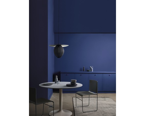 Esszimmer mit rundem Tisch, Stühlen und Hängeleuchte vor blauer Wand