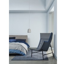 Helles Schlafzimmer mit Bett, Sessel, Teppich und Pendelleuchte