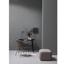 Arbeitszimmer mit Schreibtisch, Stuhl, Hocker und Dekoration in einem hellen Raum.