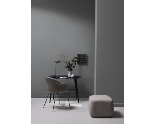 Arbeitszimmer mit Schreibtisch, Stuhl, Hocker und Dekoration in einem hellen Raum.