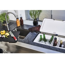 Outdoor-Küche mit Spüle, Schneidebrett, Zutaten, Getränken und Kühlbox.