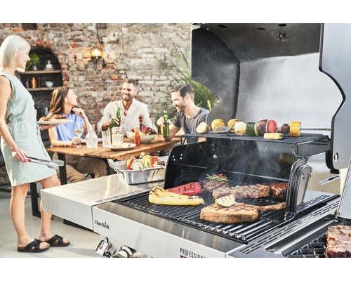 Szene im Freien mit Menschen, die um einen Holztisch sitzen und ein Barbecue mit einem Char-Broil Grill zubereiten.
