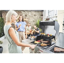 Szene mit Personen, die an einem Grill mit Grillgut stehen