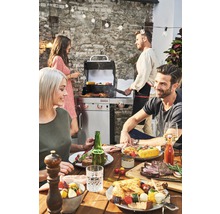 Grillszene im Freien mit Tisch, Grill und feiernden Menschen
