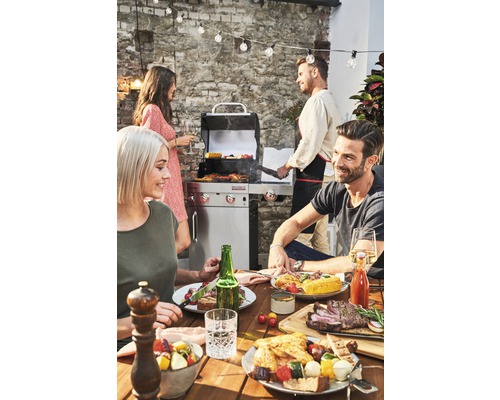 Grillszene im Freien mit Tisch, Grill und feiernden Menschen