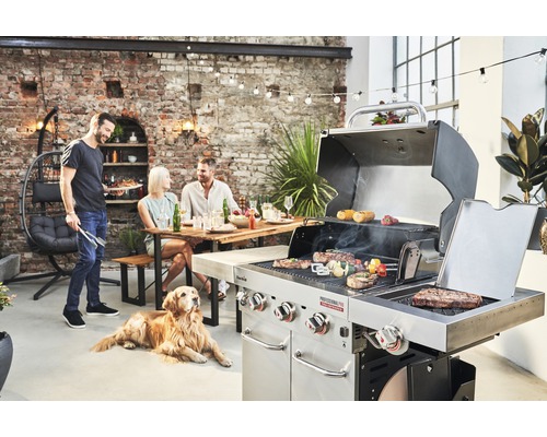 Personen grillen im Freien mit einem Gasgrill von Char-Broil, während ein Hund zusieht.