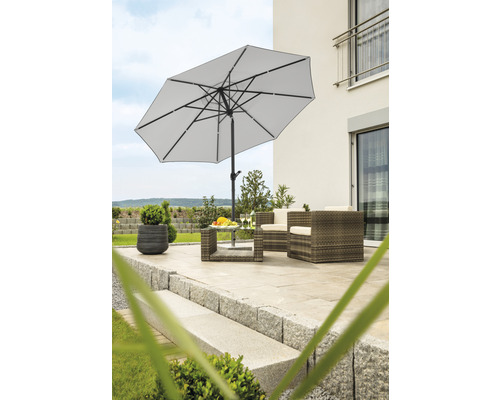 Terrasse mit Sonnenschirm, Tisch und Sitzgruppe aus Rattan