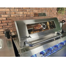 Buschbeck Grill mit Brathähnchen auf dem Grillspieß vor einer Backsteinmauer