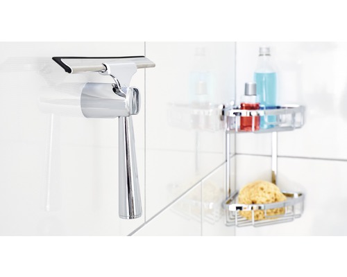 Duschabzieher aus Metall mit Halterung an gefliester Wand montiert, mit Duschutensilien im Hintergrund