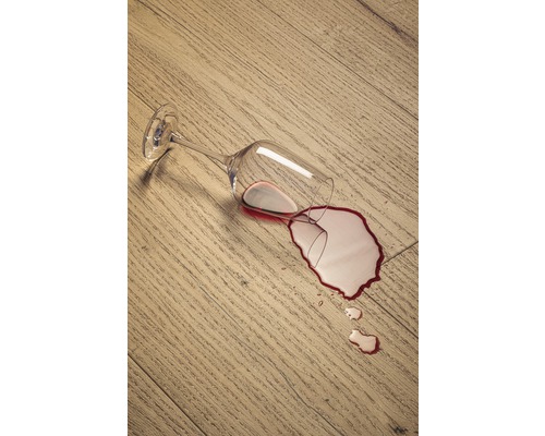 Umgefallenes Weinglas auf einem Holzboden mit ausgelaufenem Wein