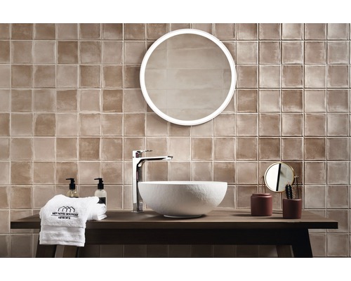 Helles Badezimmer mit braunen Fliesen, rundem Spiegel und modernem Waschtisch