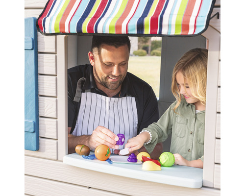Vater und Tochter spielen an einem Spielhaus-Fenster mit Spielzeugessen.
