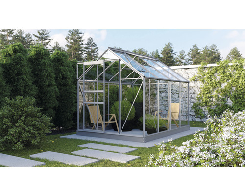 Ein Gewächshaus mit Pflanzen und Stühlen in einem Garten.