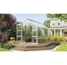 Gewächshaus im Garten mit Pflanzen und Gartenmöbeln auf einer Holzterrasse vor einem Wohnhaus.